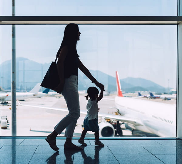 Mother holding child’s hand, walking through airport